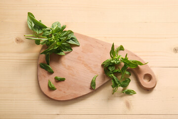 Cutting board with fresh green basil leaves on wooden background