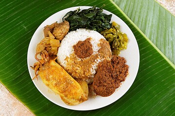 Nasi Padang served with spicy beef rendang, omelette, cassava leaves, and sambal hijau. Popular Indonesian traditional food from West Sumatra.