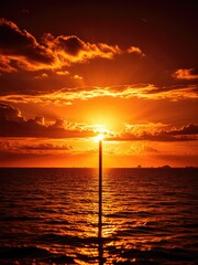 Vibrant sunset over ocean, golden light illuminating water. Dramatic clouds and calm sea