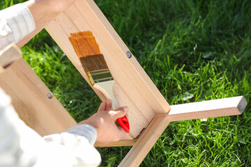 Woman painting wooden step stool in garden, closeup