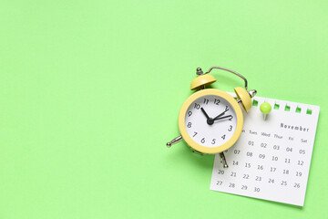 Calendar with alarm clock and paper pin on green background