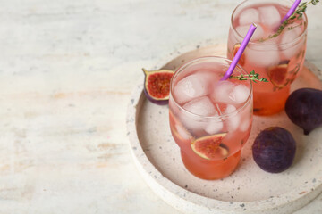 Glasses of tasty fig lemonade with thyme and fruits on white background