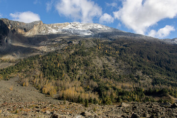 Autumnal mountain landscape with a rocky scree slope, mixed forest, and snow-dusted peaks at Hope Slide Site, BC, Canada