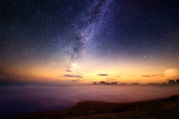 Fototapeta premium Milky Way Galaxy Over Cloud Sea and Distant City Silhouette