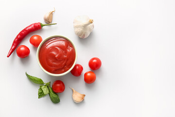Bowl of tasty tomato sauce with basil leaves, garlic and chili pepper on grey background