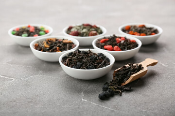 Bowls with different fruit tea on grey grunge background