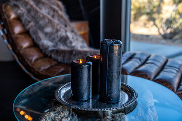 Black candles burning flame on silver platter with glass table