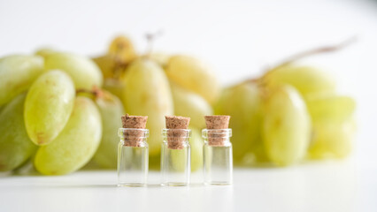 Three small glass vials with cork stoppers in front of a bunch of green grapes. Concept of grape juice testing, laboratory research and food quality control. Photo