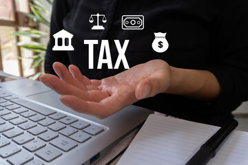 A woman is holding a laptop with a hand on it and the word tax is written on the screen. Concept of taxation and the importance of paying taxes
