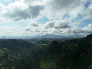 Aerial view of a lush green mountain covered with dense tropical forest under a bright blue sky and...
