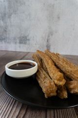 Vertical shot of churros on a plate, accompanied by hot chocolate. Mexican food