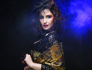 Fashionable woman with creative makeup and hairstyle posing on dark blue background.