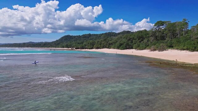Aerial view of lonely surfer at tropical island coastline, Plengkung Beach,Alas Purwo National Park, East Java, Indonesia