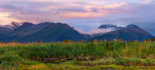 Panoramic view of scenic mountain landscape with low lying clouds under twilight in Alaska near Valdez.