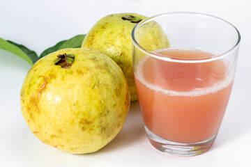 A glass of refreshing guava juice sits beside two whole guavas, offering a healthy and flavorful.