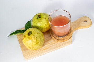 Fresh guava juice in a glass with ripe guavas on a wooden board presents a healthy and refreshing.