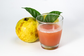 Freshly squeezed guava juice in a glass with a whole guava fruit and leaves, perfect for a healthy.