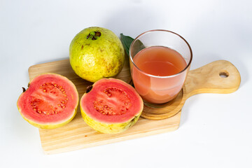Fresh guava fruit and juice are arranged on a wooden board, showcasing their vibrant colors and.