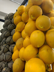 Golden honeydew and cantaloupe melons stacked high create a vibrant, healthy display perfect for market fresh food promotions and summer fruit ads