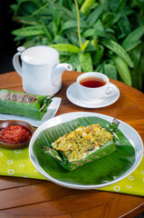 Grilled rice with shredded chicken and green chilies, wrapped in banana leaves, traditional...