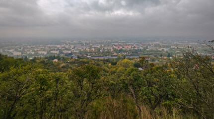 Wide panoramic view from the Eszterházy rock shelter near Szelim Cave, overlooking Tatabánya and the Vértes hills under dramatic autumn clouds.