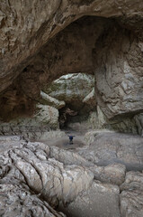 A lone hiker stands beneath the immense limestone dome of Szelim Cave in Tatabánya, Hungary. A spectacular karst formation and prehistoric shelter.