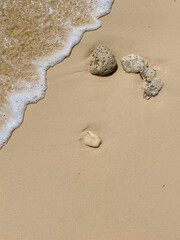 Small waves washing stones on sandy shore.