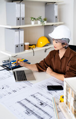 Senior female engineer designer or contractor working on drawing plans analyzing structure on...