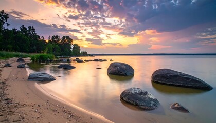 Calm lake sunset scene with scattered rocks and trees