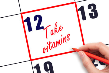 12 th day of the month.  Hand writing Take vitamins reminder and drawing red frame on calendar with red pen on white background. concept of health care. Planning and scheduling