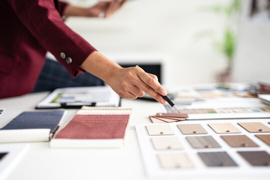 close up hand of Professional interior designer working in the office, asian female architect working on business of Real estateproject , sketching on a house plan choosing swatches and material. - Powered by Adobe