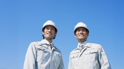 青空の下で前を見つめる若手作業員の二人