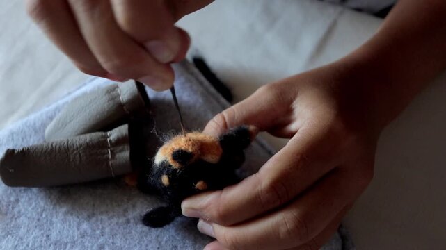 Artisan crafts detailed, Precise hand motions shaping delicate animal features expertly, Closeup view of craftsman refining tiny felt animal face with careful needlework