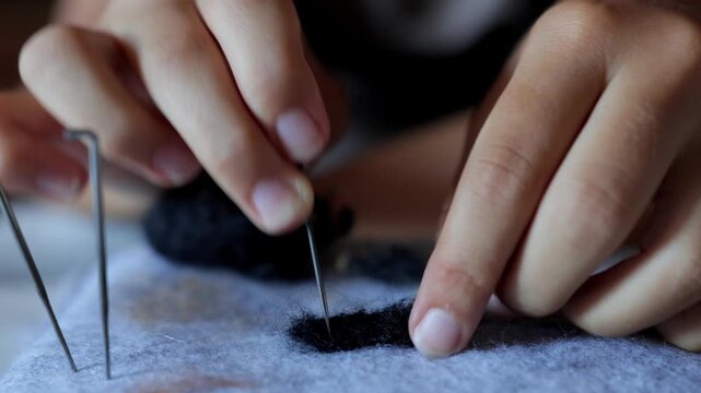 Detailed crafting process, Hands carefully refine felt on cushion surface, Focused craftsmanship showcasing detailed smoothing and finishing of felt on cushion surface
