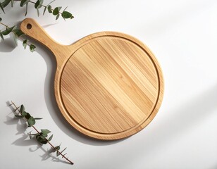 Rustic wooden pizza peel with eucalyptus leaves casting shadows on a white surface