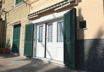 Old street, road in Italian countryside near sea. Traditional building. Sun day. Entrance, window to house. Nature and flowers. 