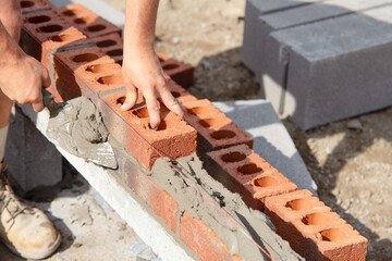 Construction worker bricklayer lays bricks for new structure at building site using tools and...