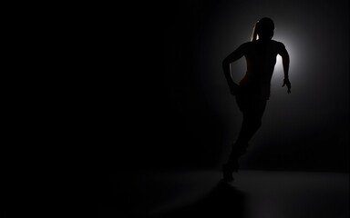 Silhouette of athletic woman running in dark background, highlighting fitness, determination, and motion in a dynamic sports scene. High quality