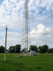 Communication tower rising against a cloudy blue sky.