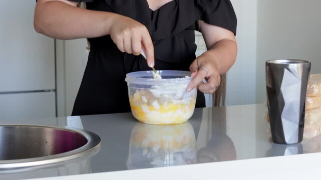 Egg mixture preparation, Blending components inside clear container on kitchen counter, Seamlessly combining eggs and ingredients in visible kitchen setting for baking