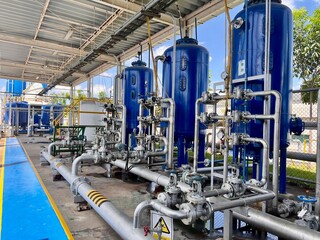 Industrial air compressor and filtration system with blue storage tanks and stainless steel piping, part of a modern factory utility system for compressed air and process control.