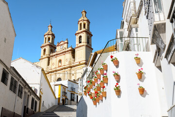Olvera village street with white buildings, potted flowers, and parish church in olvera,cadiz,spain