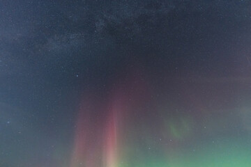 A magical celestial background of the star-filled night sky featuring the Milky Way and a vibrant red and green aurora.