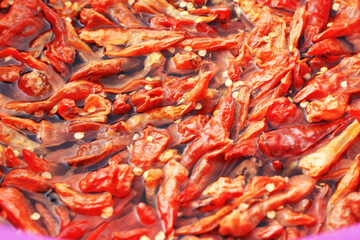 An extreme close-up, top-down view of dried red chilies and seeds soaking in water, creating a vibrant and detailed food texture background.