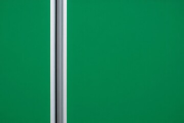 Abstract vertical metallic pole against a solid green background