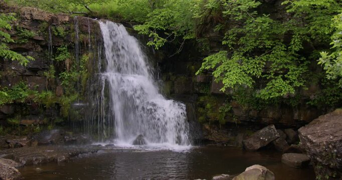 Extra Wide shot of water cascading over rocks at East gill force, waterfall, through trees on the river swale, keld, Swaledale