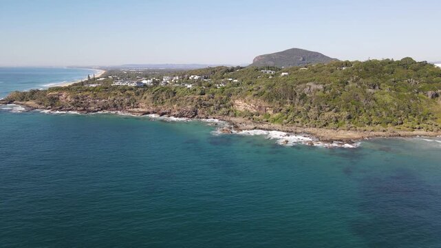 Drone aerial moving forward towards a coastal area in coolum beach on a sunny day
