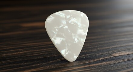 A single white pearlescent guitar pick rests on a dark wooden surface for commercial usage and mockups