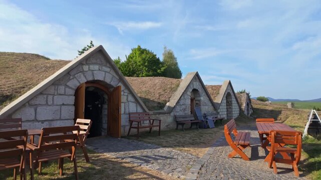 Open winery cellar with outdoor tables and benches waiting for guests at Kőporosi Pincesor, Hercegkút, Hungary.