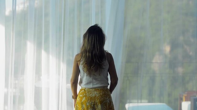 Woman pulling aside the terrace curtains